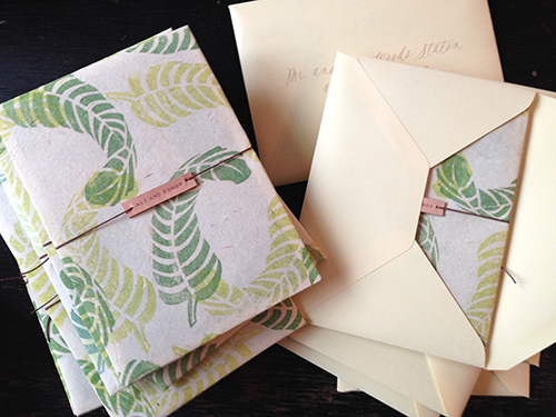 Invitation for Cartagena, Columbia wedding with hand stamped banana leaves on lokta paper with leather name tag by Shindig Bespoke