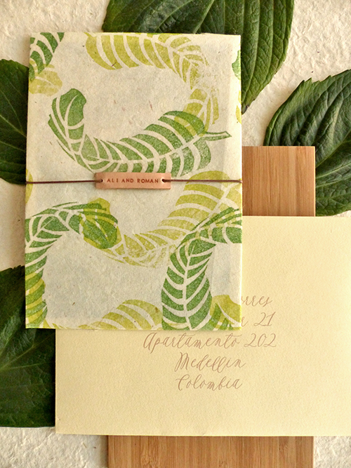 Wedding invitation with hand stamped banana leaves on lokta paper with leather name tag by Shindig Bespoke