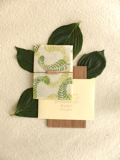 Wedding invitation with hand stamped banana leaves on lokta paper with leather name tag by Shindig Bespoke