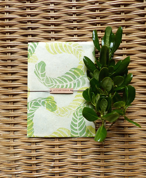 Wedding invitation with hand stamped banana leaves on lokta paper with leather name tag by Shindig Bespoke